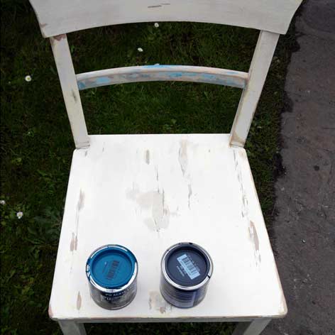 abgeschliffener Küchenstuhl mit zwei Farbtöpfen auf der Sitzfläche